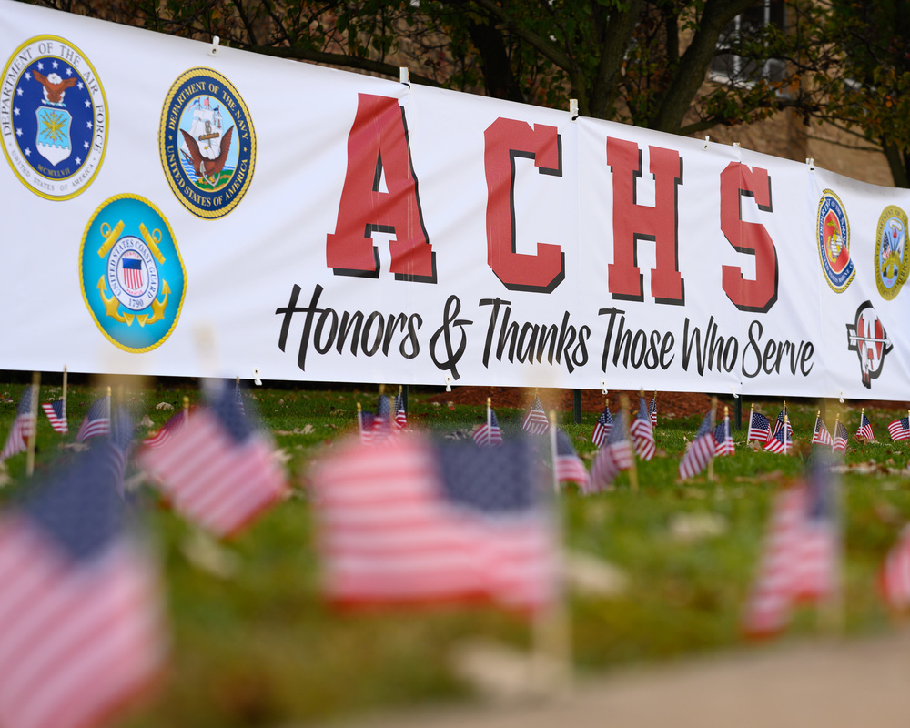Small American flags in front of a banner that reads ACHS Honors & Thanks Those Who Serve