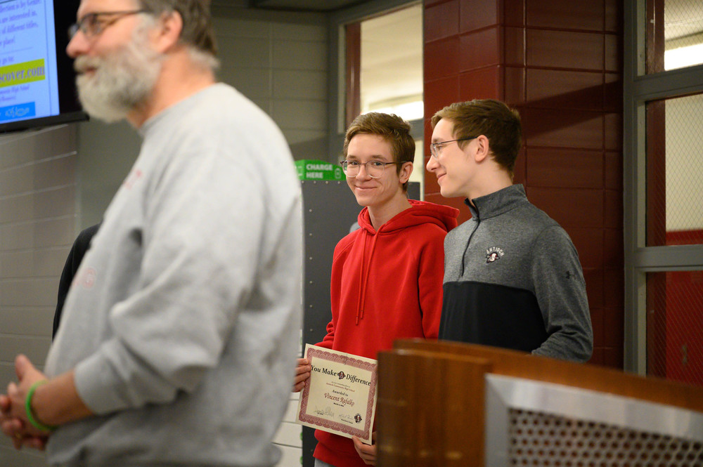 Two boys stand in cafeteria with certificates.