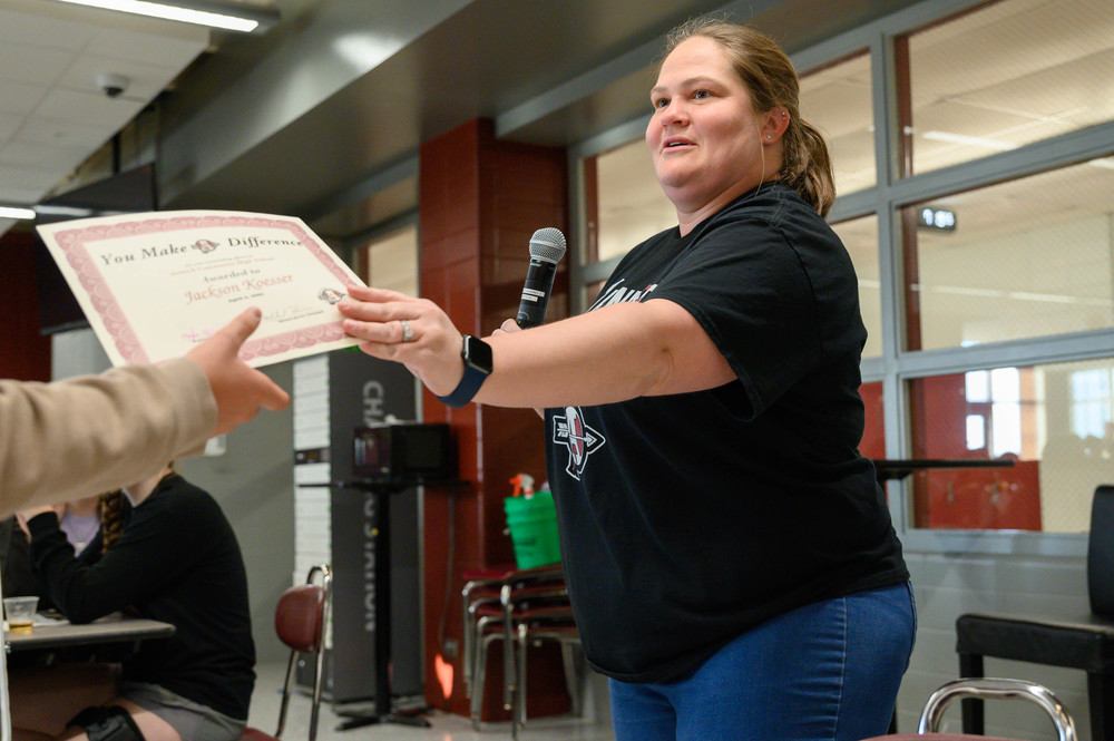 teacher hands out certificate in cafeteria